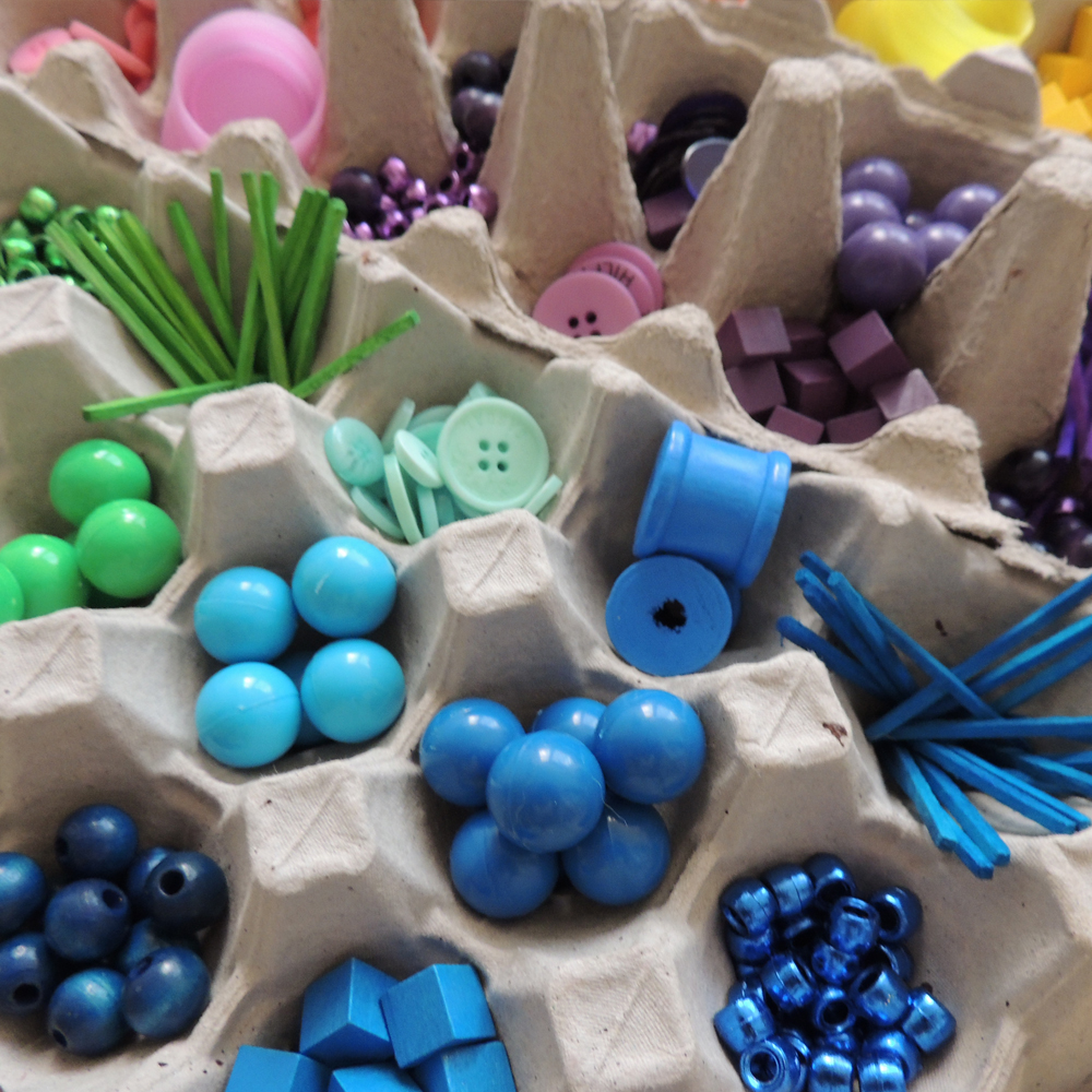 A selection of colourful beads and other loose parts stored in egg cartons