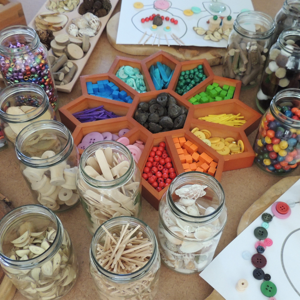 Well organised image of loose parts stored in a sorting tray and glass jars