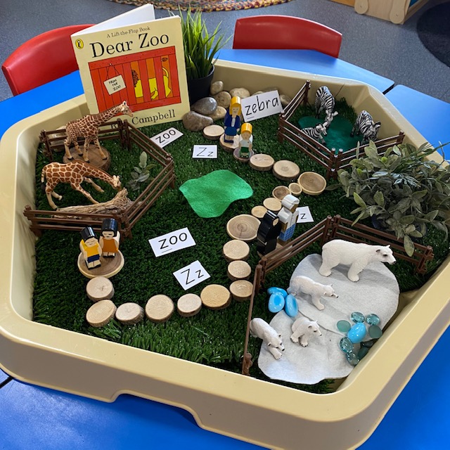Dear Zoo Hex Tray activity featuring book animals and wooden blocks on grass