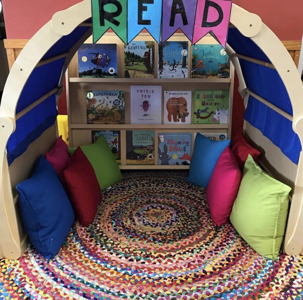 Cosy reading corner with a rug, cushions, and book shelf