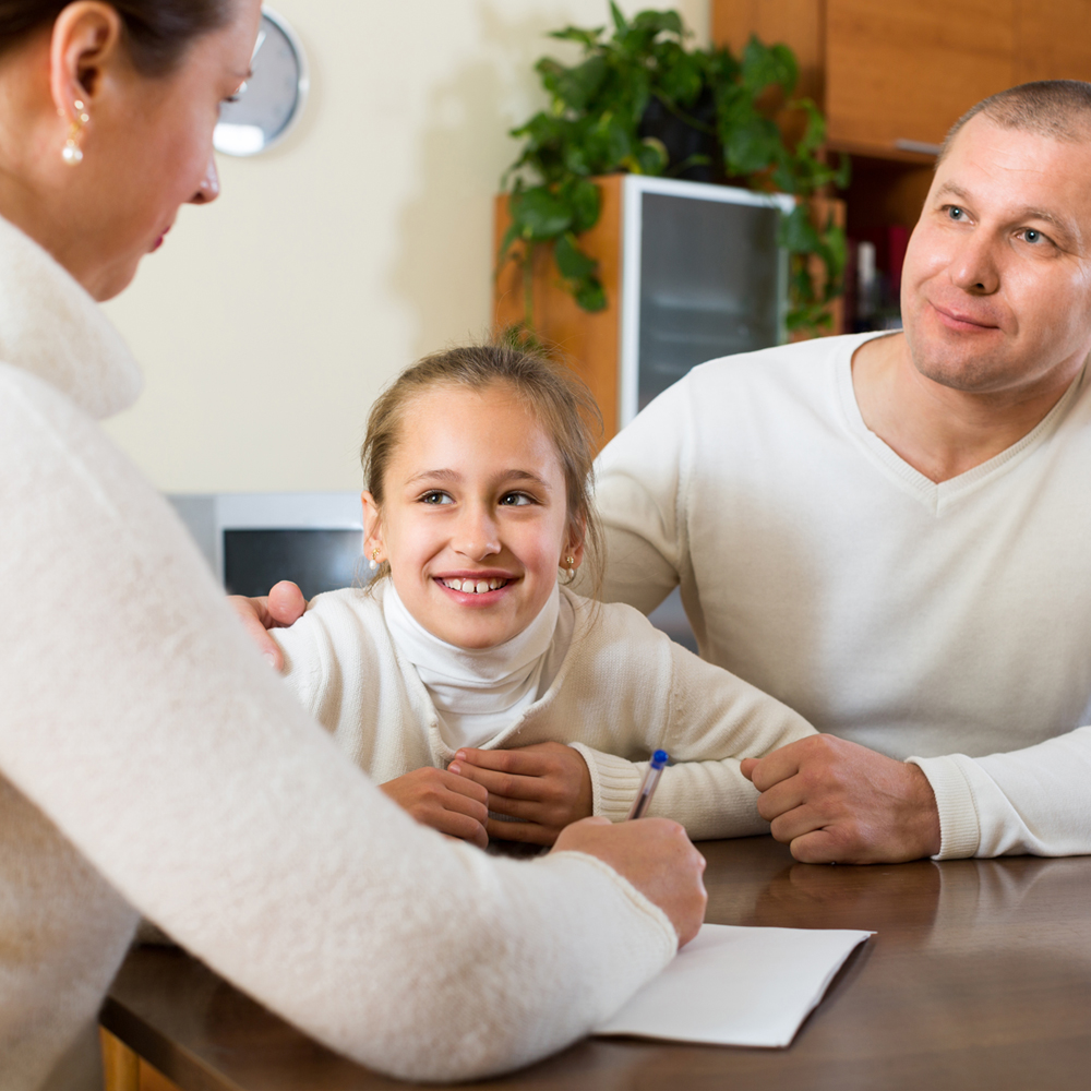 Young girl sitting at a table with parents 