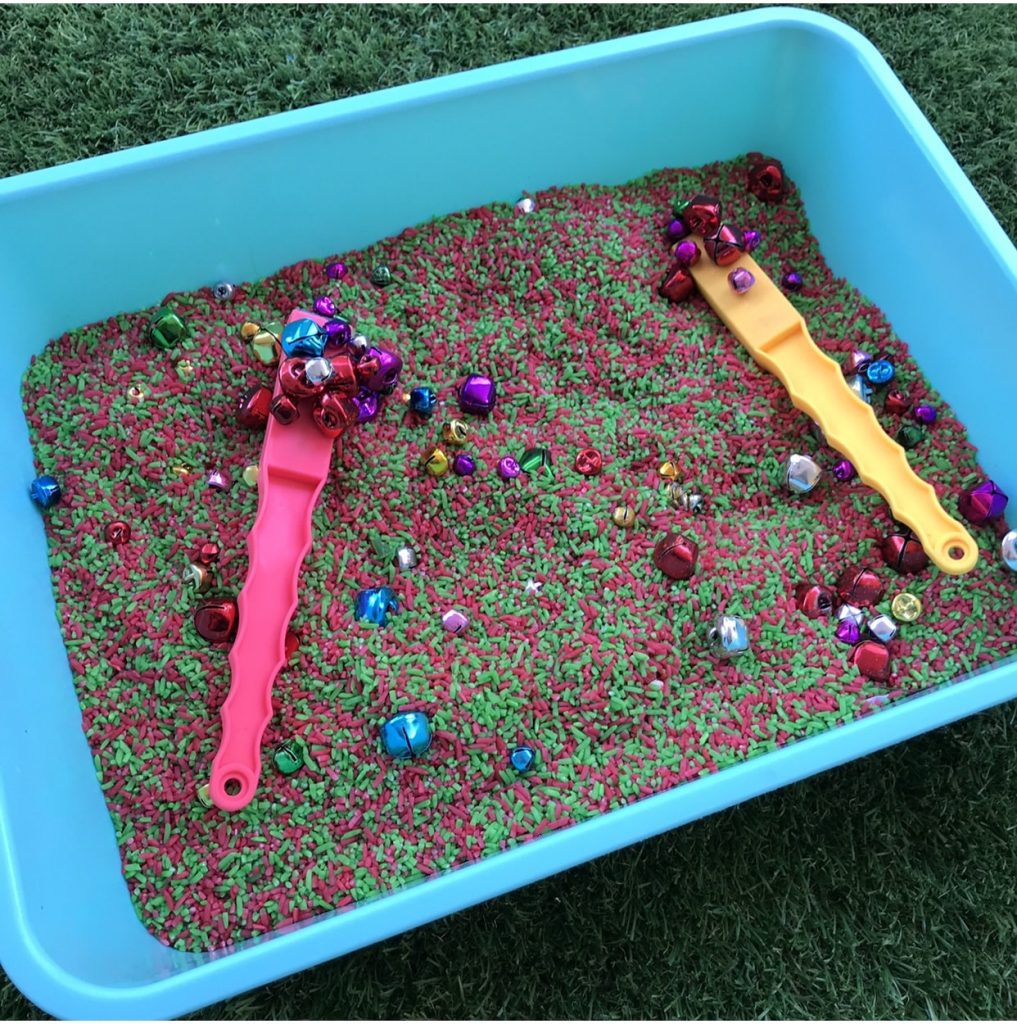 Sorting christmas bells in coloured rice with magnet wands