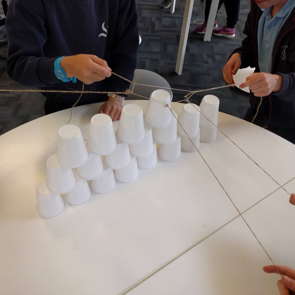 Makerspace cup towers challenge close up with kids hands