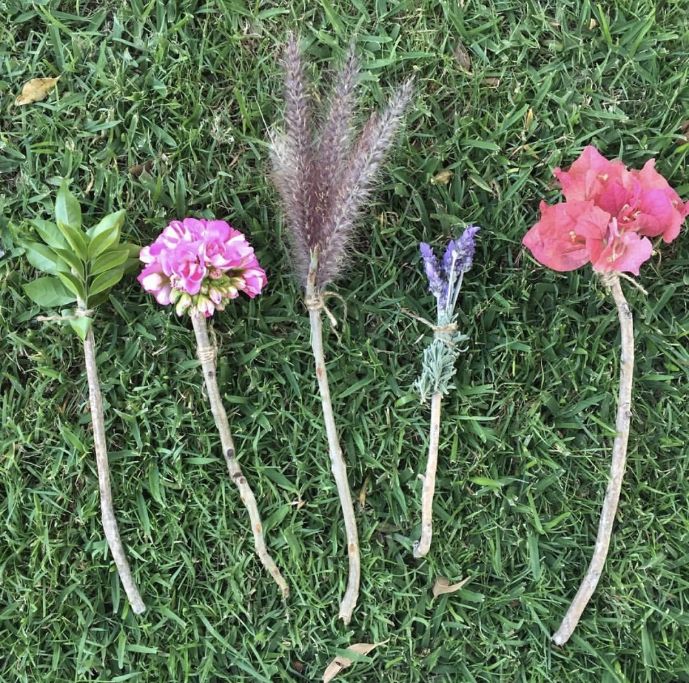 Flowers tied to sticks with string to produce paint brushes