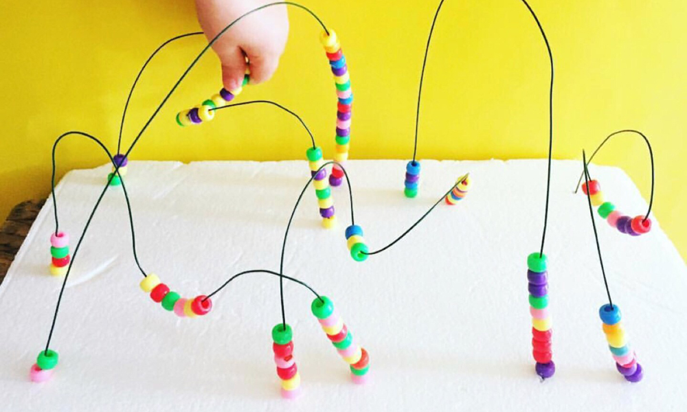 Child moving beads around a wired maze