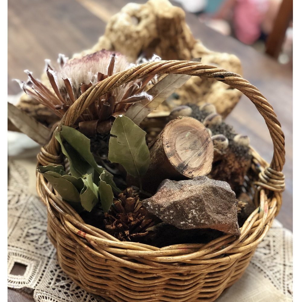 Basket filled with wood logs and leaves as well as other natural materials