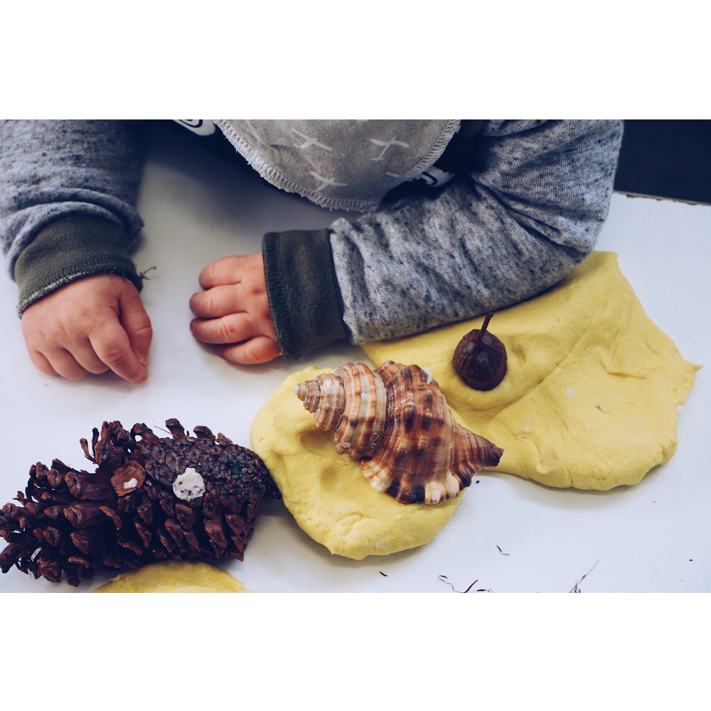 Child with pine cone and shells 