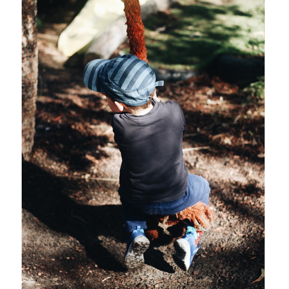 Child playing on rope swing from tree