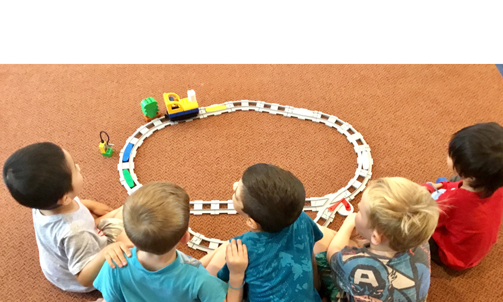 Five children sat on the floor playing with a Coding Express train