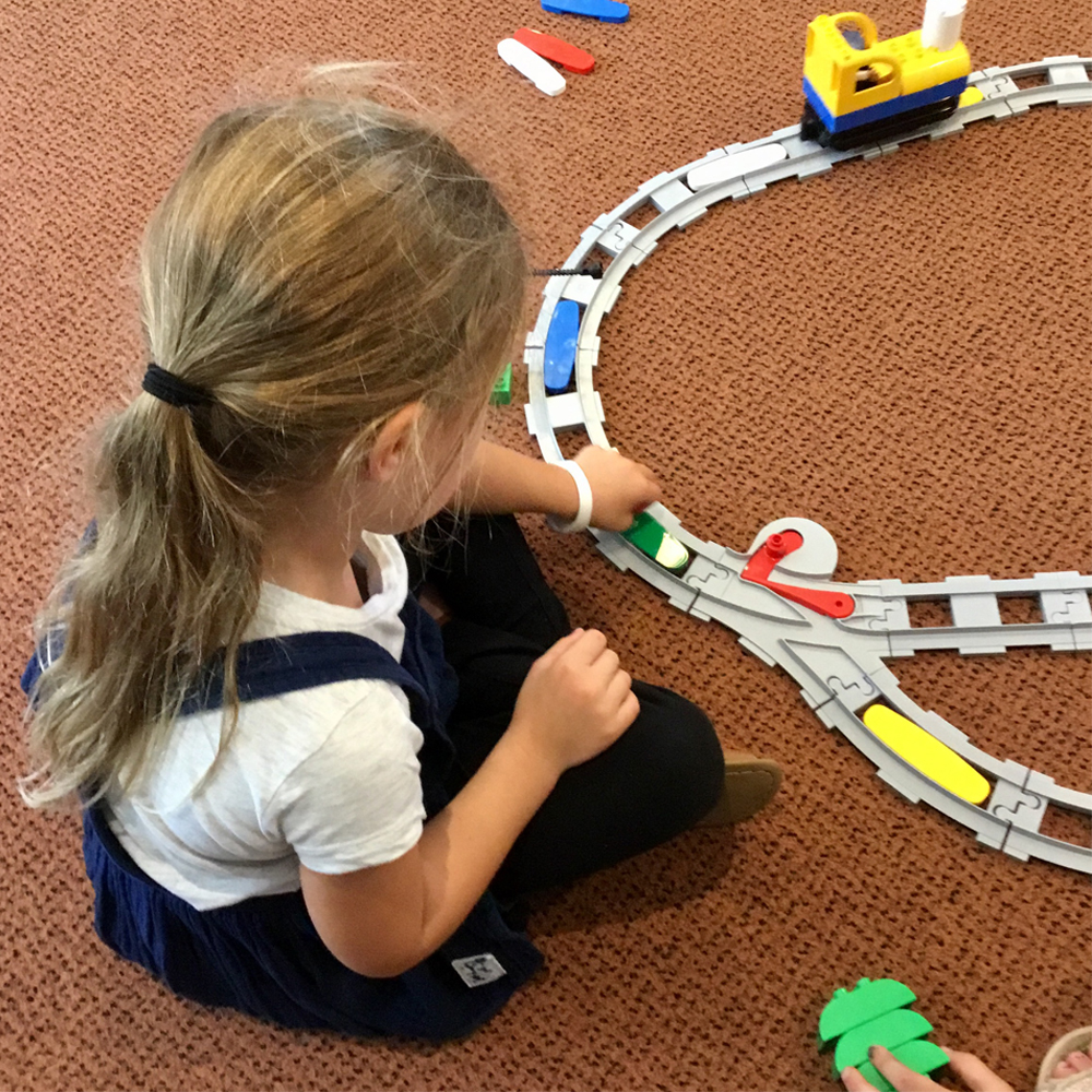 Young girl building a Coding Express train track