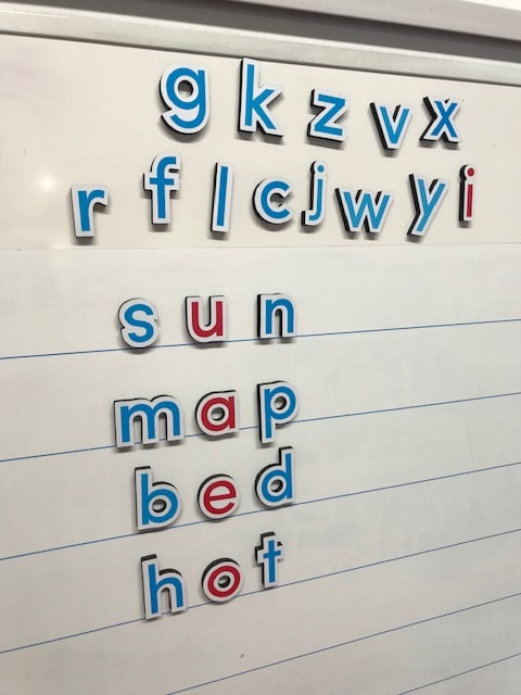 Word building with magnetic letters on whiteboard