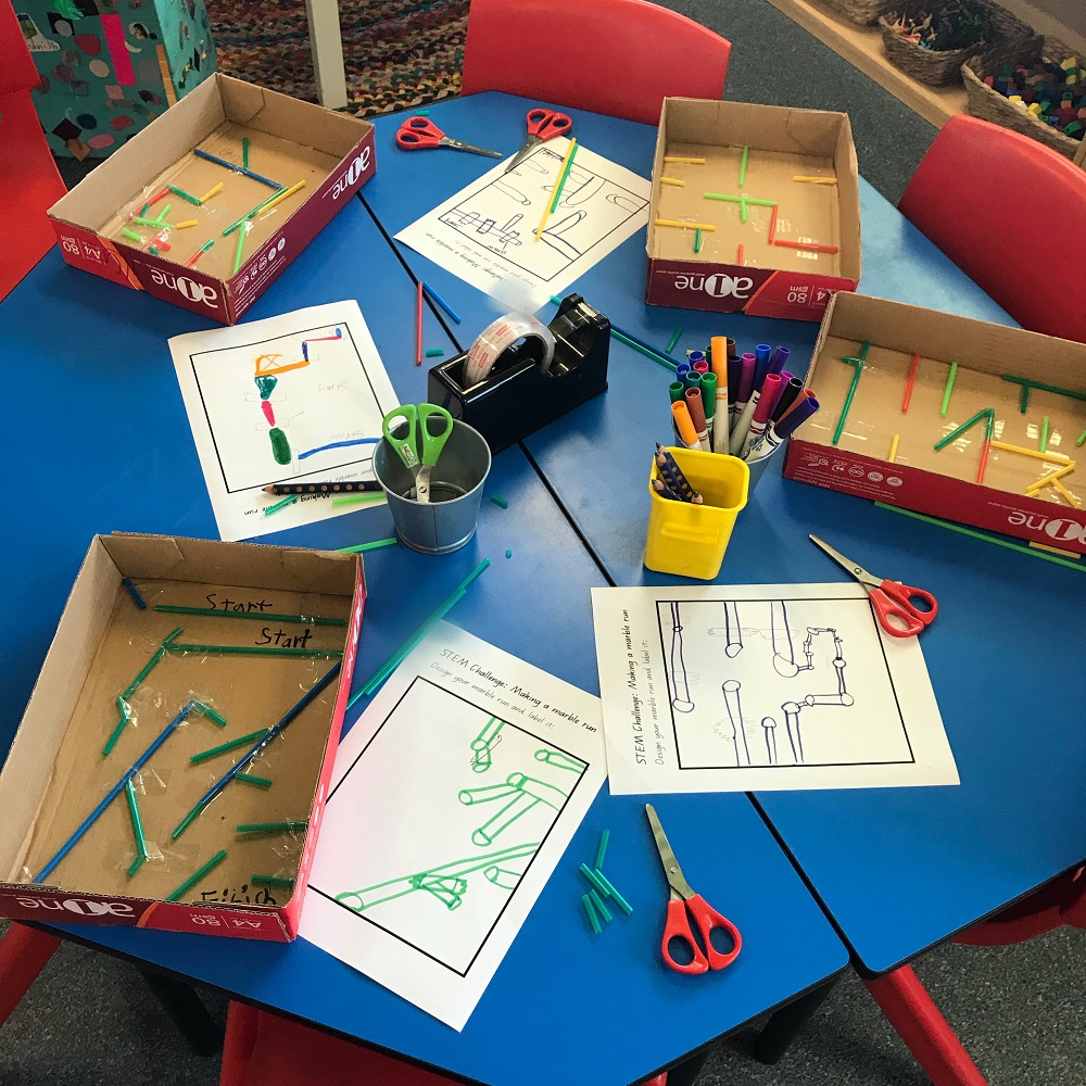 Four marble maze activities in progress on a classroom table