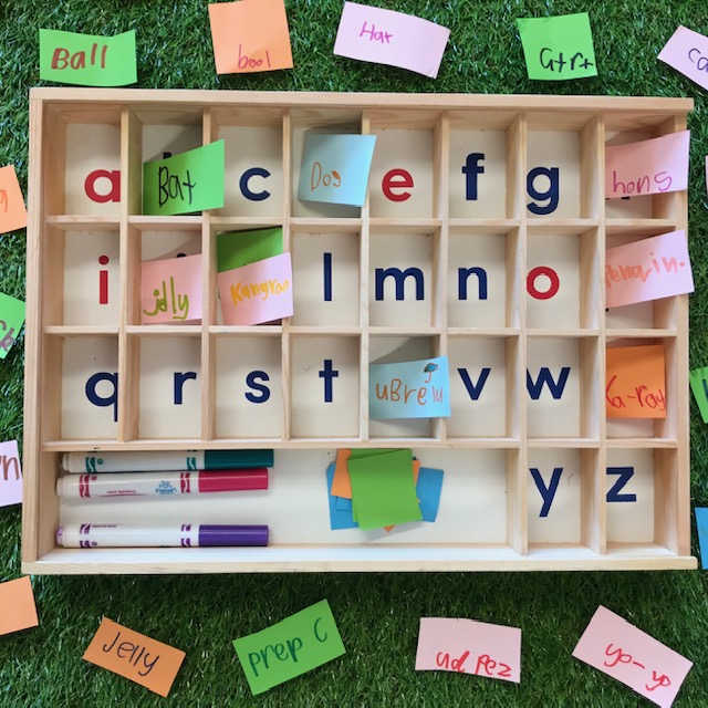 Alphabet sorting tray activity with post it notes and felt pens on a grass background