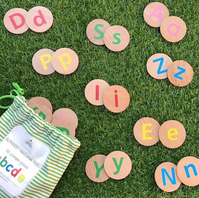 Wooden upper and lowercase alphabet discs on grass background