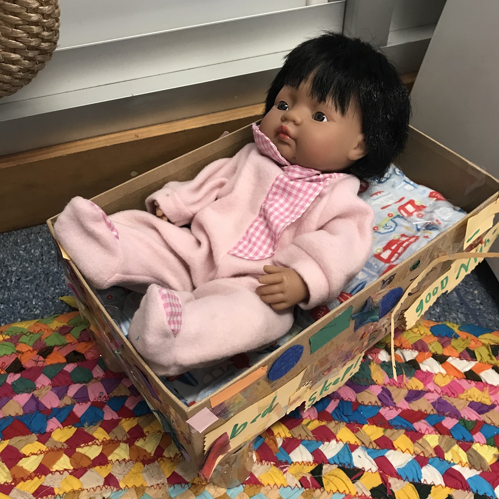 Doll in handmade cardboard box bed