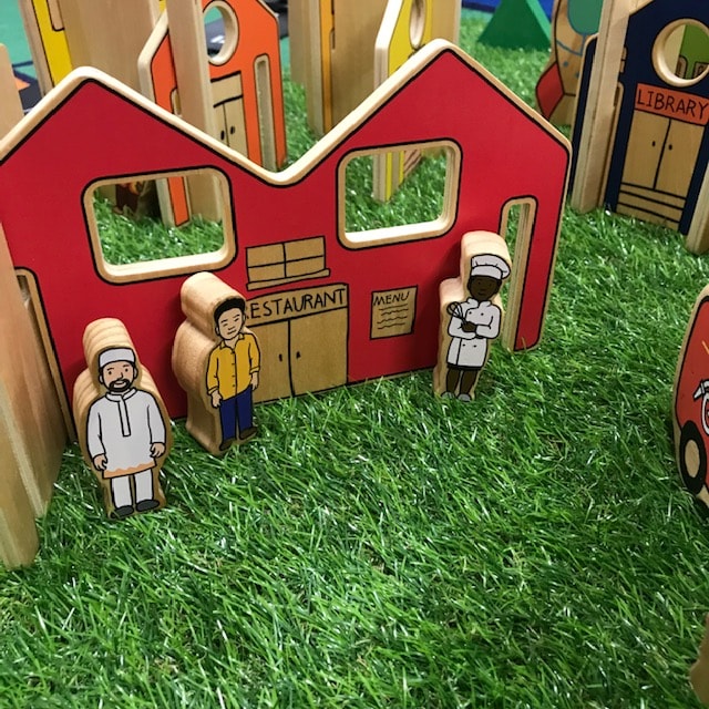 Wooden town and dolls on grass background