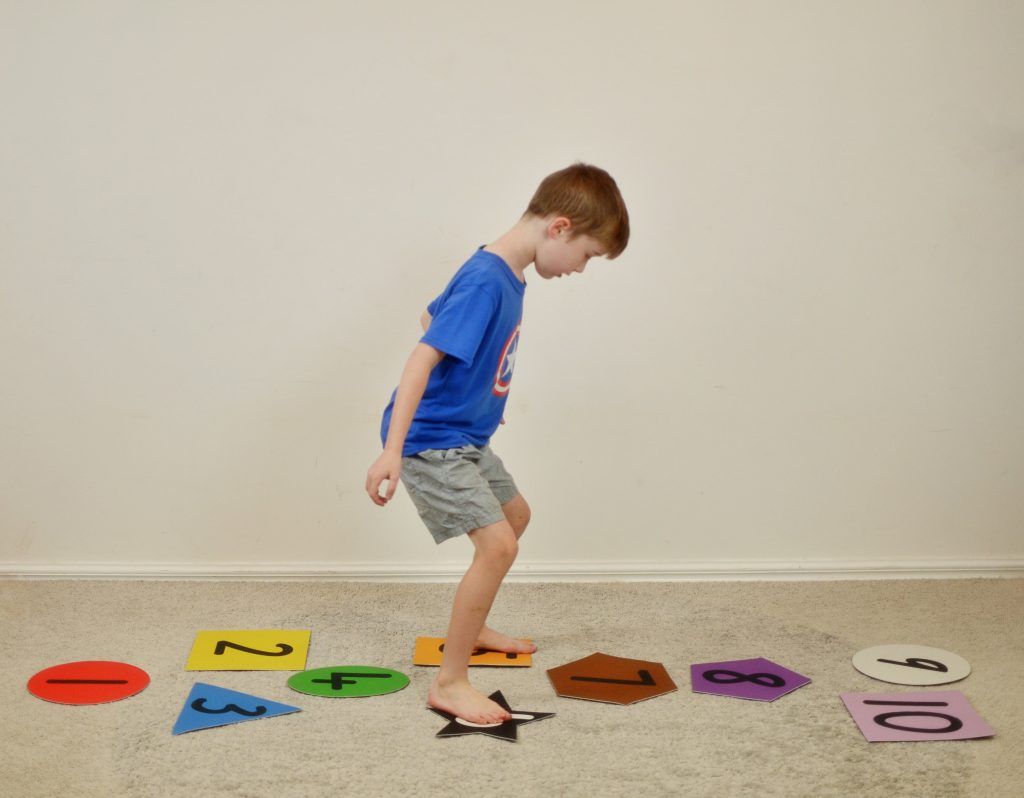 Boy playing numbered hopscotch on carpet