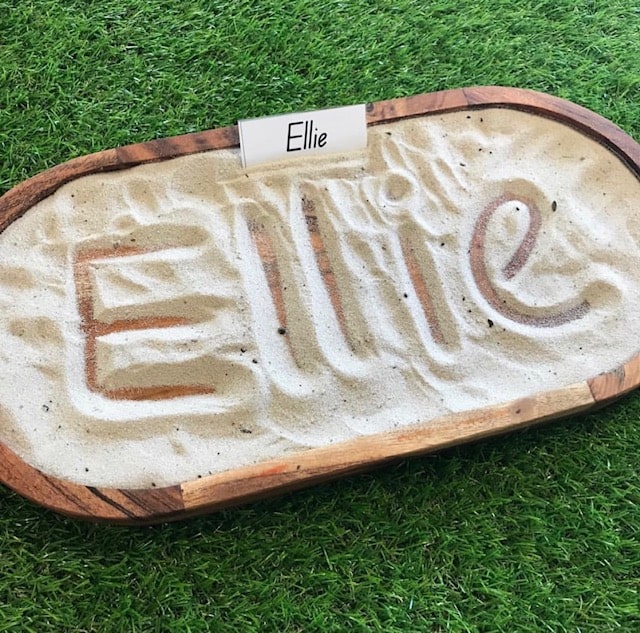Sensory sand tray writing spelling out Ellie letters