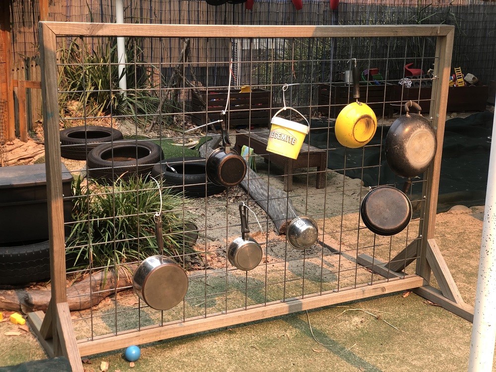 Pots and pans hanging from wooden frame in garden