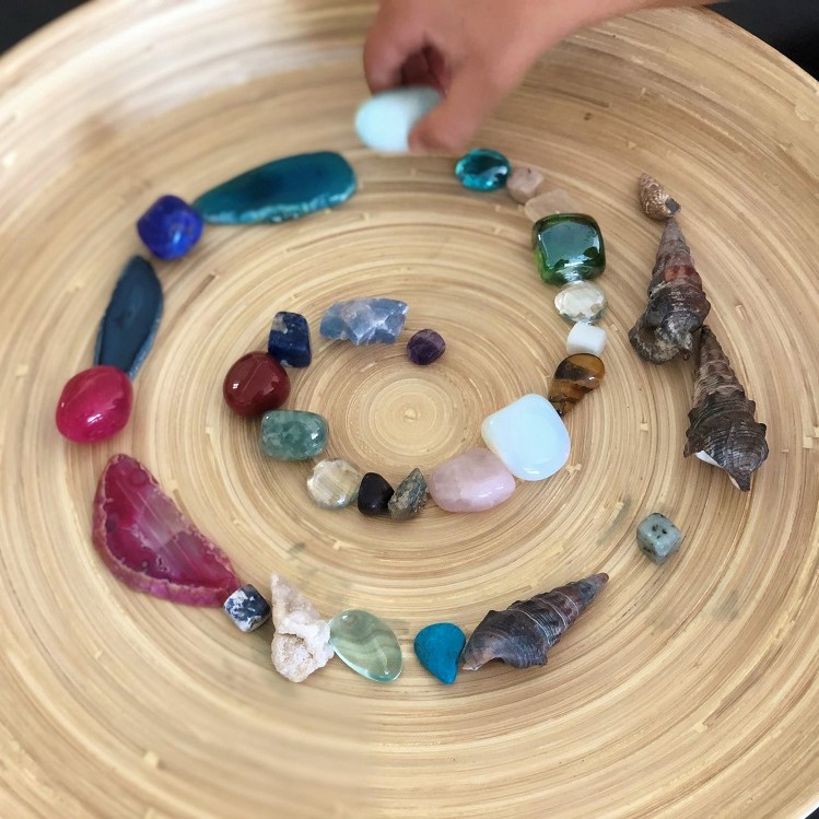 Wooden bowl with jewels stones and shell with child hand square