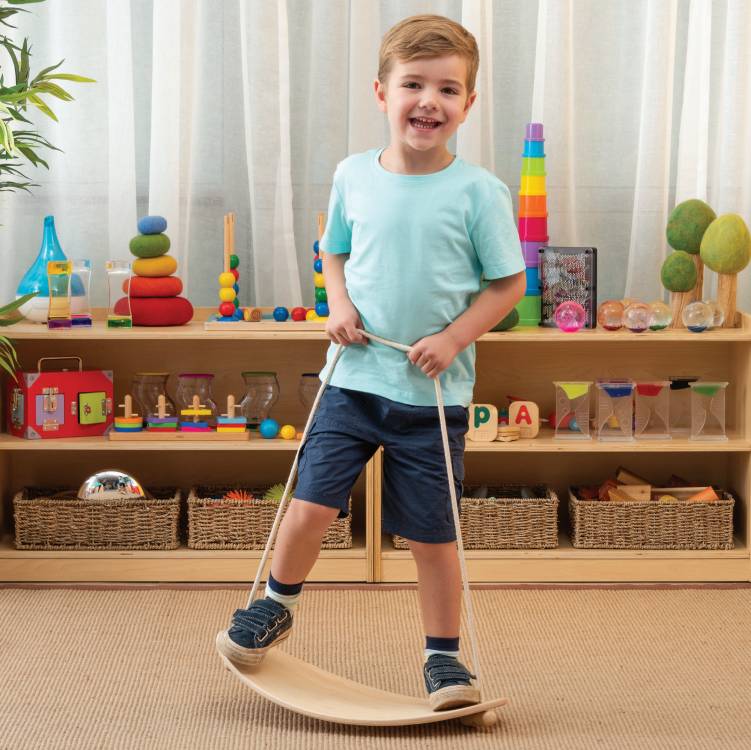 Child balancing on wooden balance board in classroom