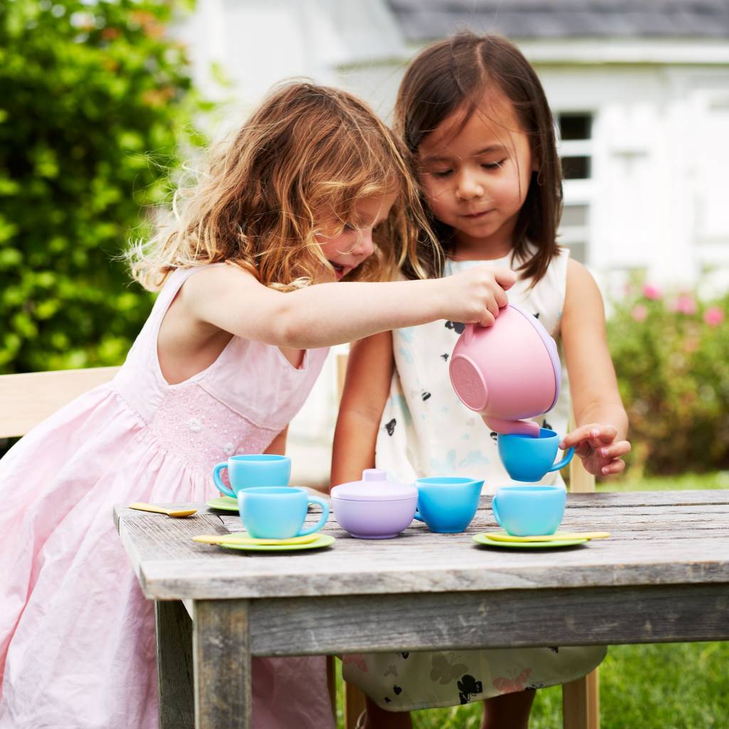 Two girls playing with a tea set outside