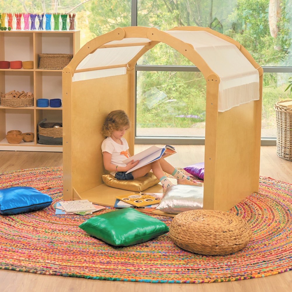 Young girl sat in cosy nook reading